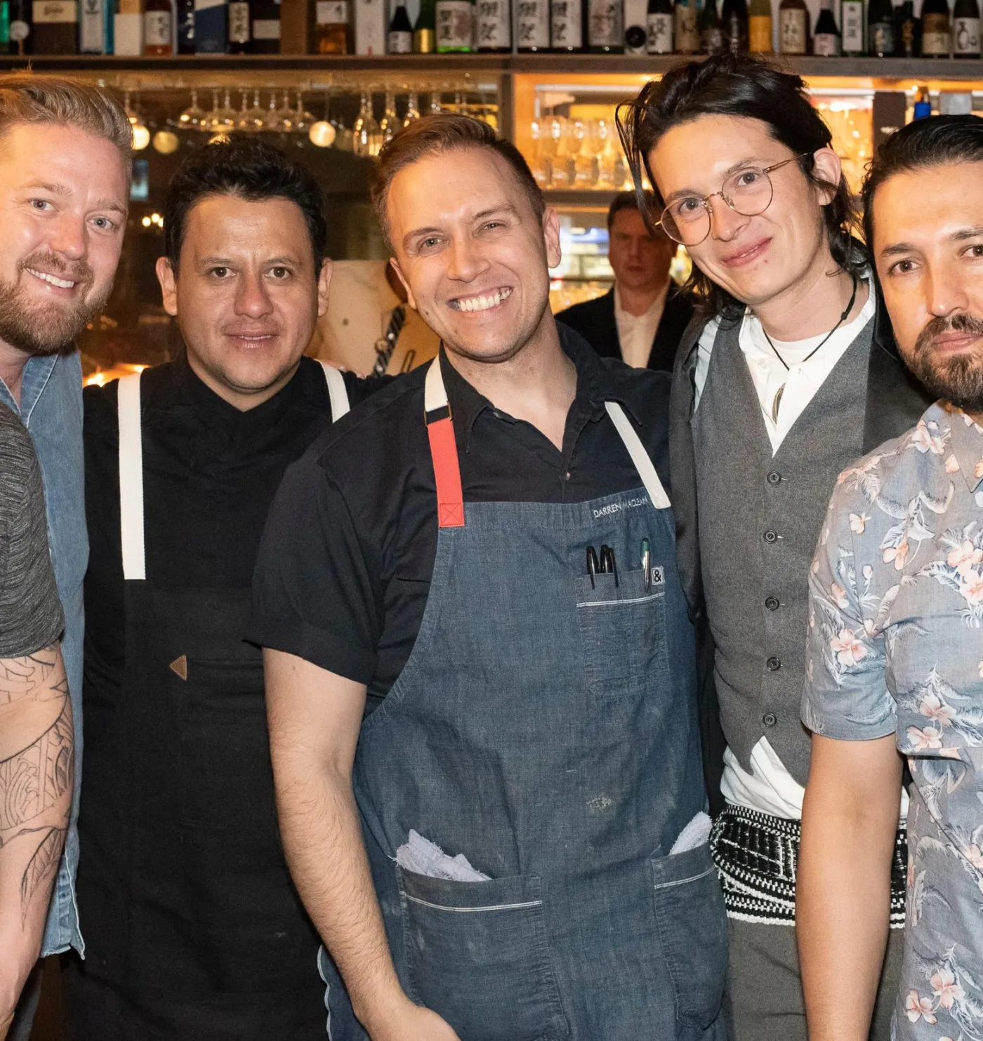 A group of chefs in aprons smiling together in a restaurant